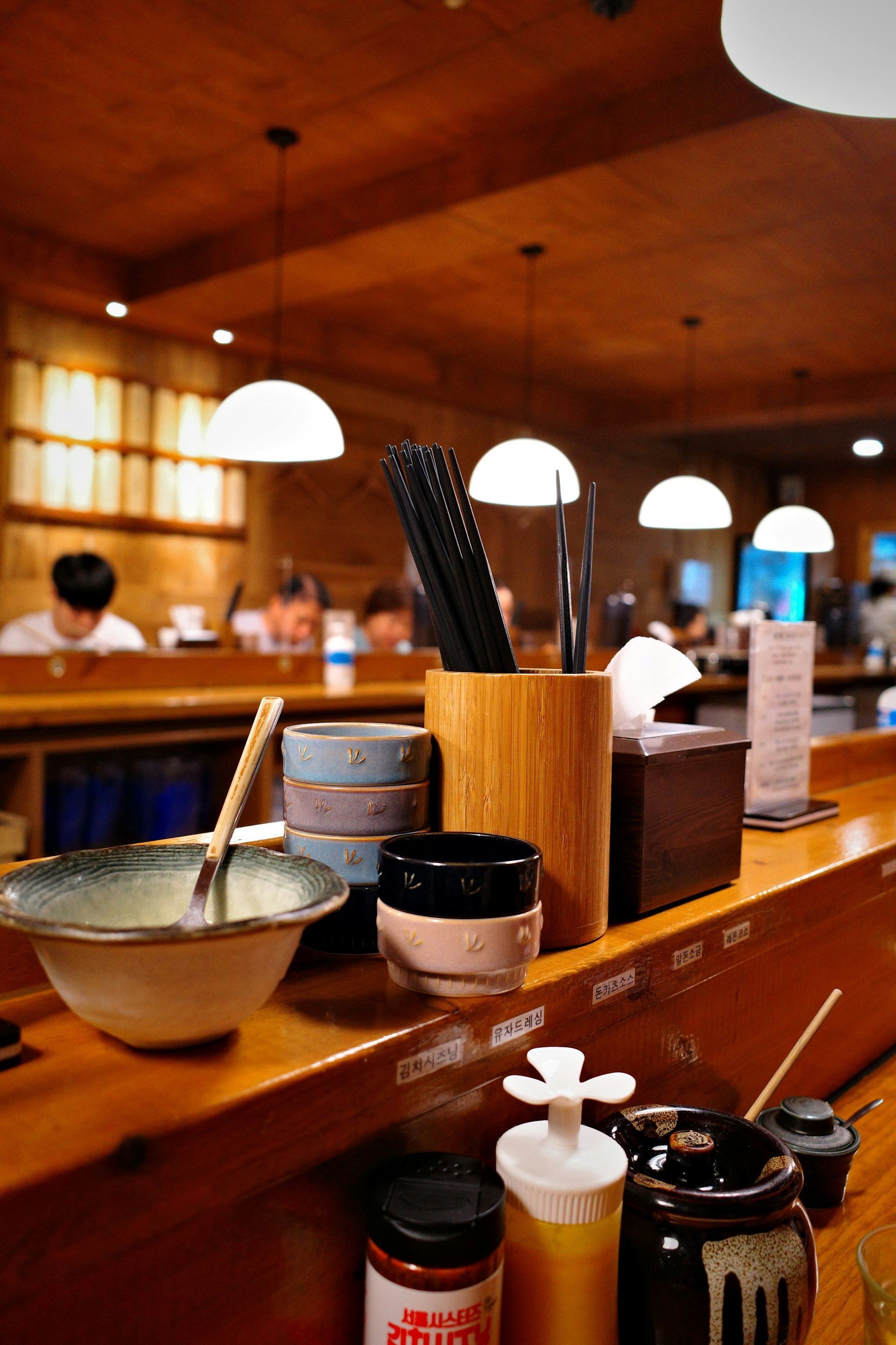 Counter with condiment jars and utensils in a warm-lit restaurant interior