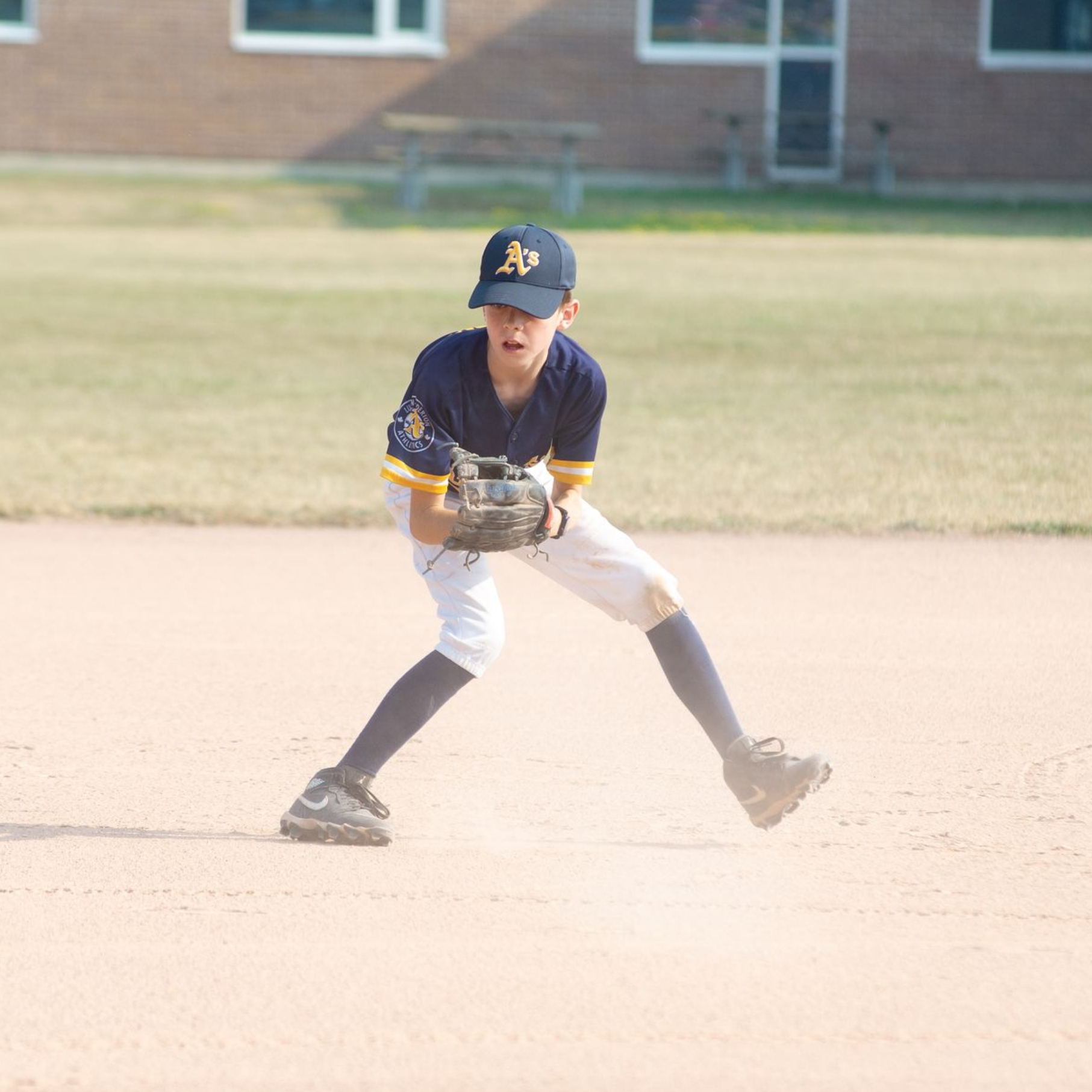 Three baseball players in blue and gold jerseys look through a chain-link fence.