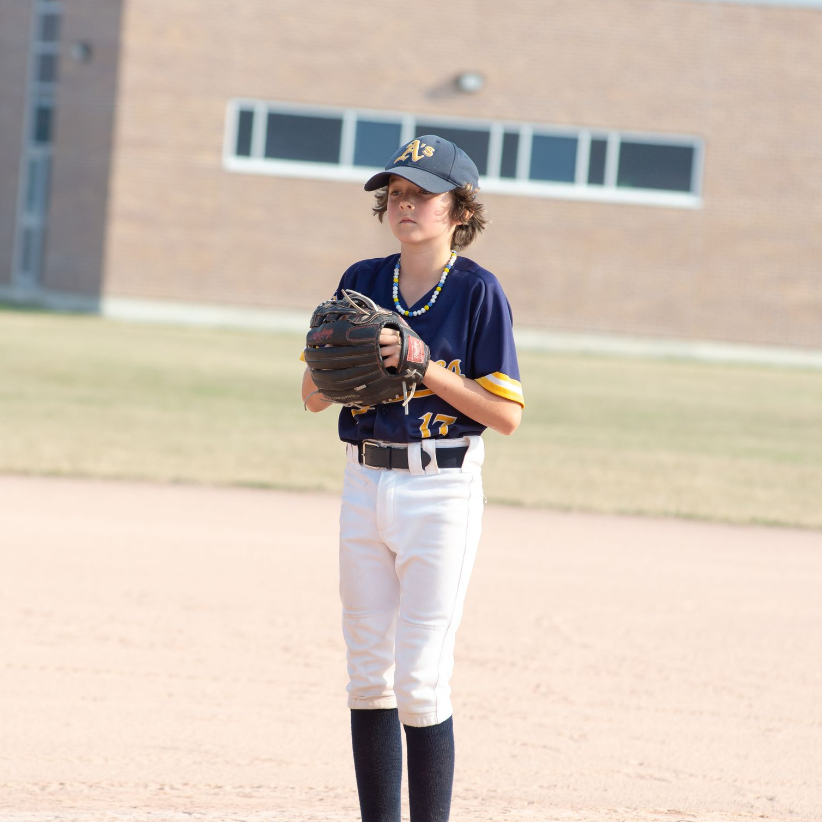 Young baseball player in Athletics uniform holding bat, ready to hit.