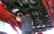 A man is working under a car in a garage.