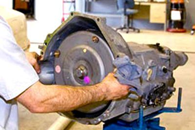 A man is working on a gearbox in a garage.