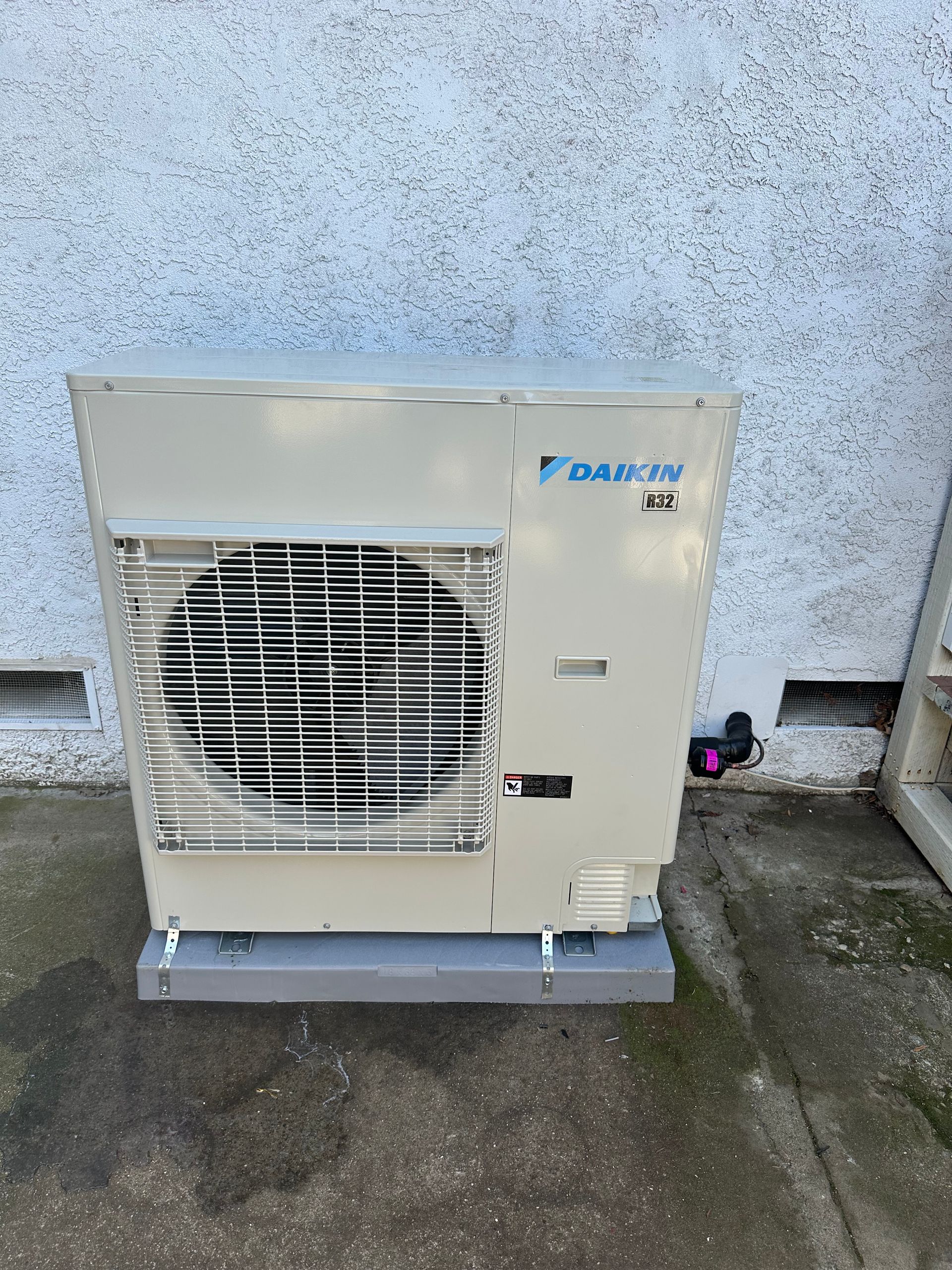 Large gray HVAC unit with exposed pipes in a basement or utility room