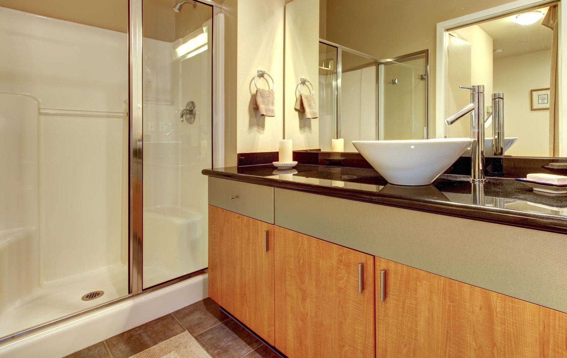 Modern bathroom with glass shower, wooden vanity, and white vessel sink