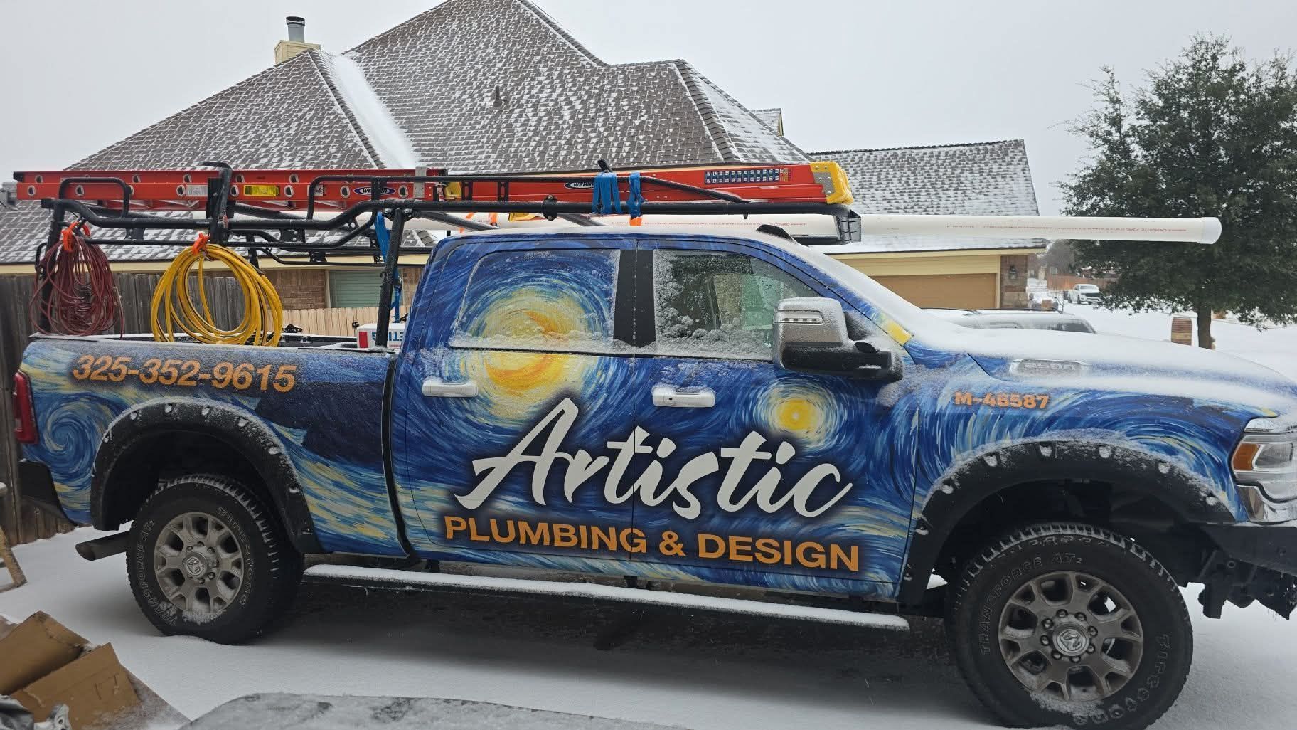 Blue Artistic Plumbing & Design service truck parked in snow beside a house, with ladder on top.
