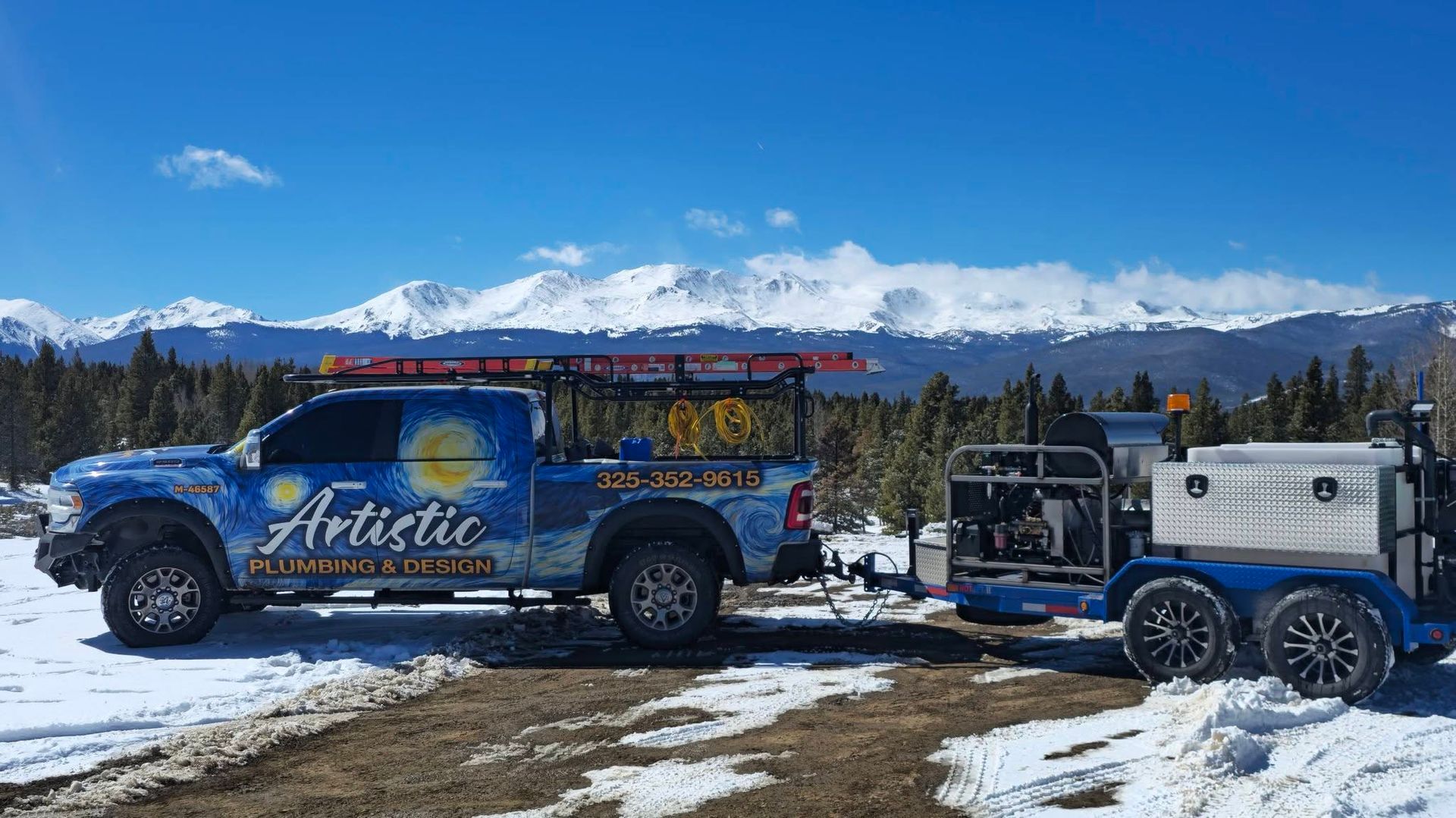 Blue Ariat pickup towing a trailer in a snowy mountain landscape