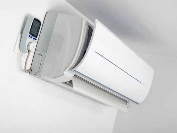 Condizionatore d'aria a parete di colore bianco con telecomando agganciato nelle vicinanze.