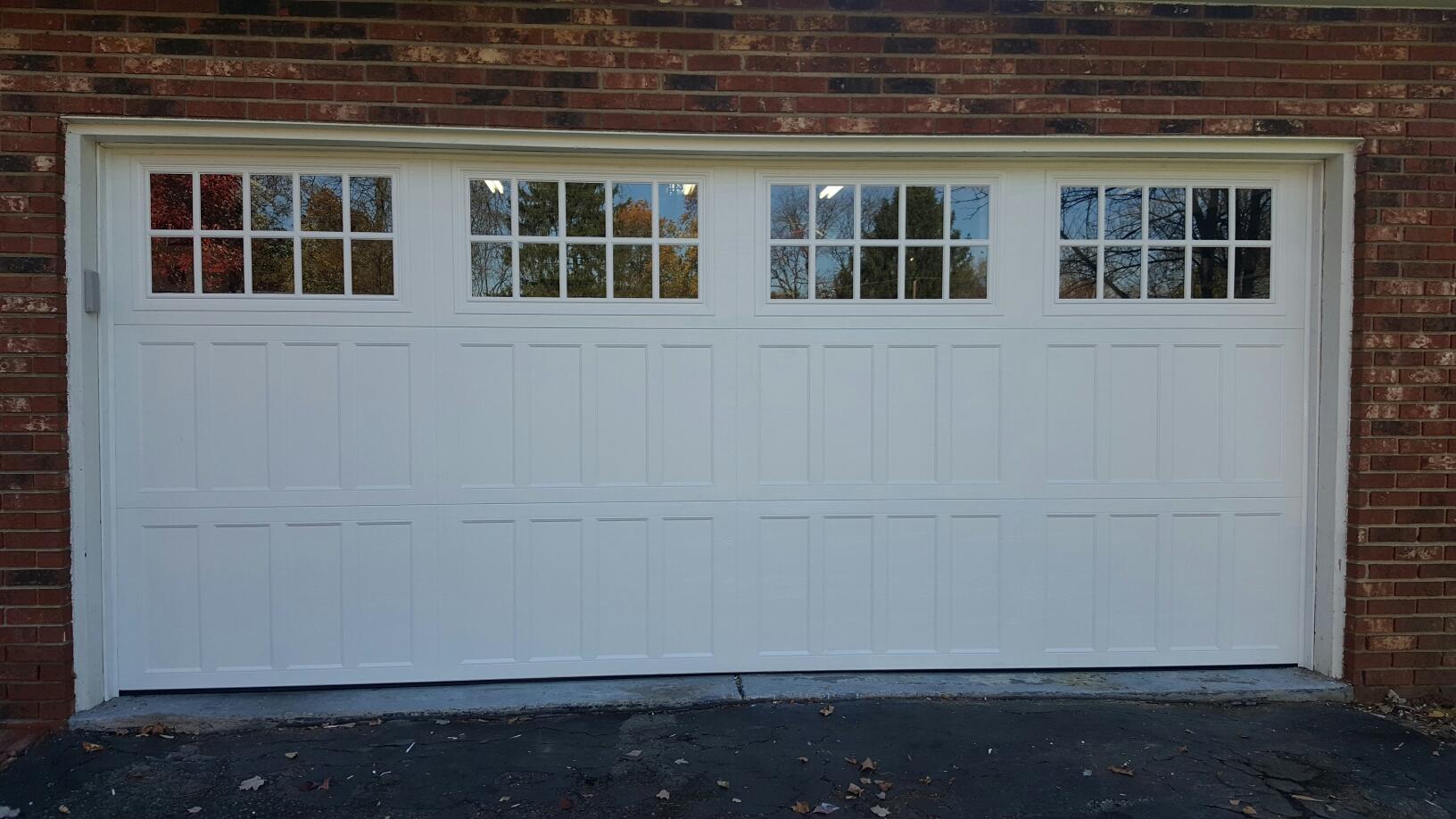 White garage door with small windows set in a brick wall