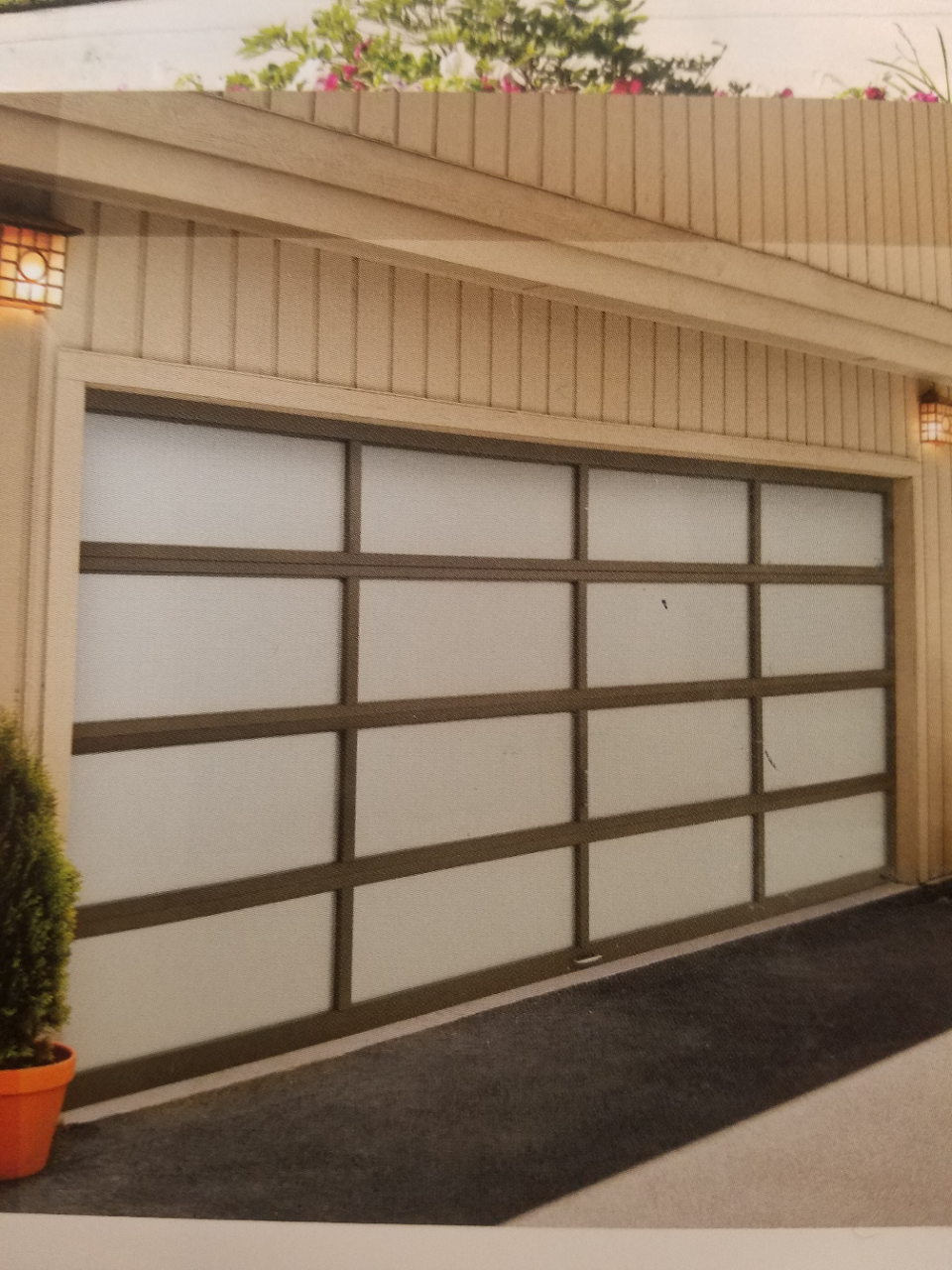 Beige garage with frosted glass panel door and dark driveway, under a slanted roof.