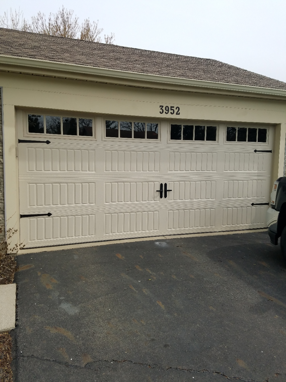 White garage door with small windows and black handle on a beige house, house number 3953 above it.