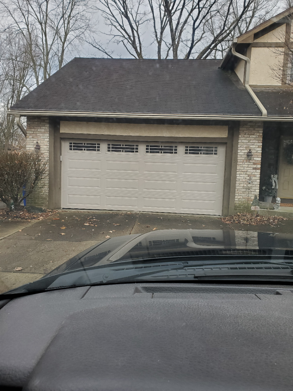 Snow-dusted suburban garage with a black car hood in the foreground