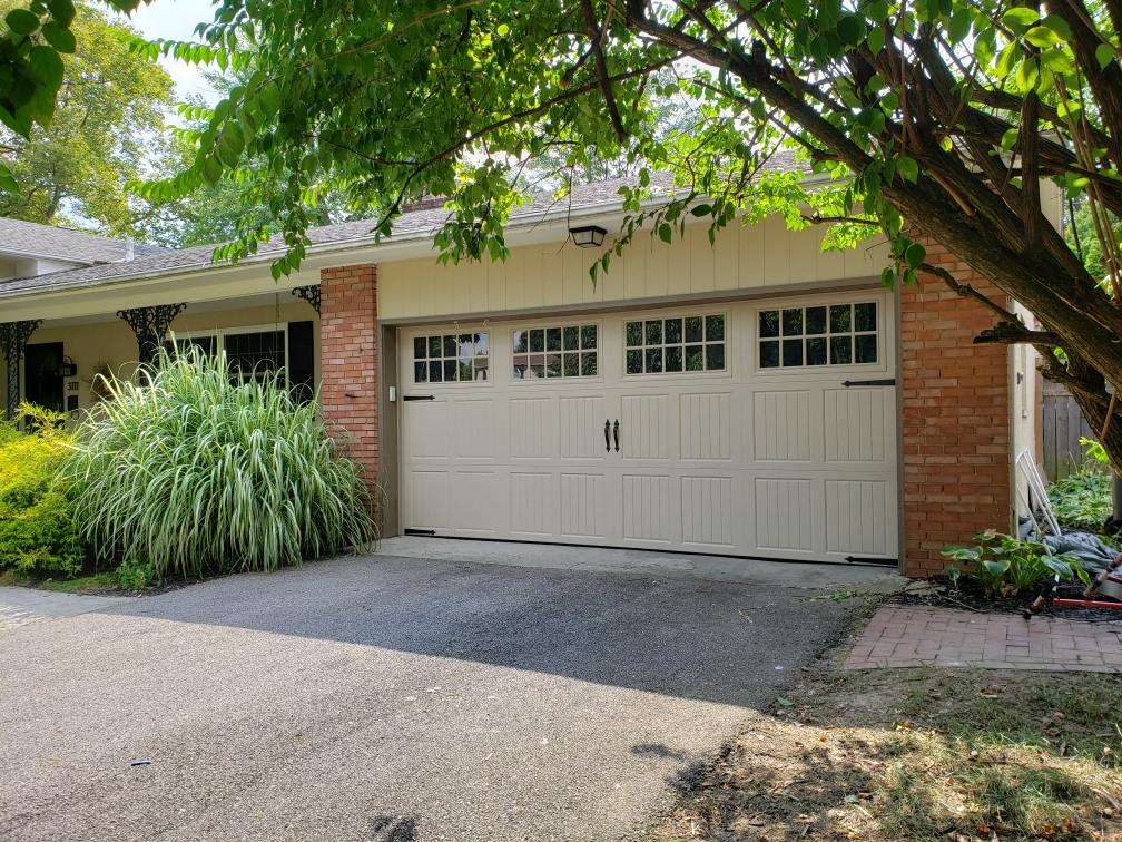 Suburban house with a double garage, brick facade, and leafy trees overhead