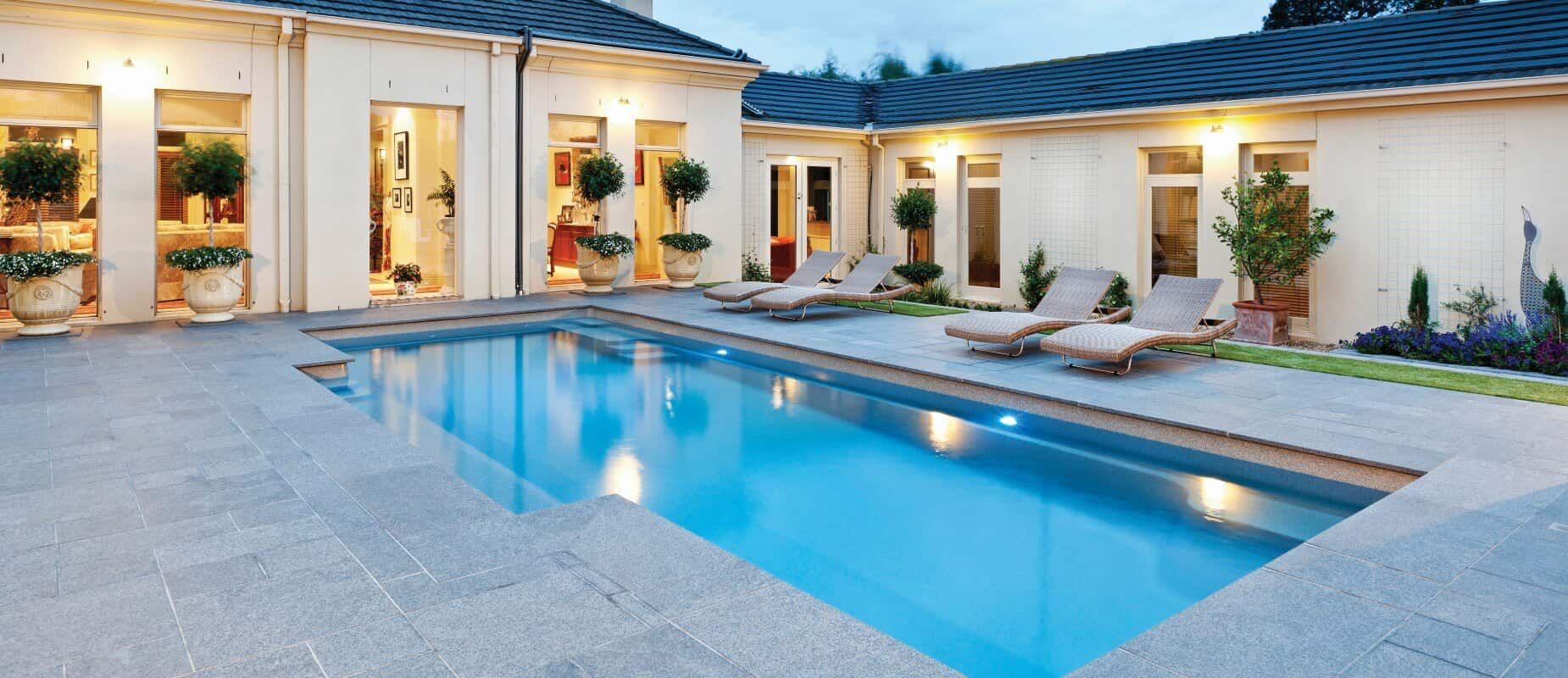 A Large Swimming Pool in the Backyard of a House With Chairs Beside It — Azure Pools Mid North Coast In Taree, NSW