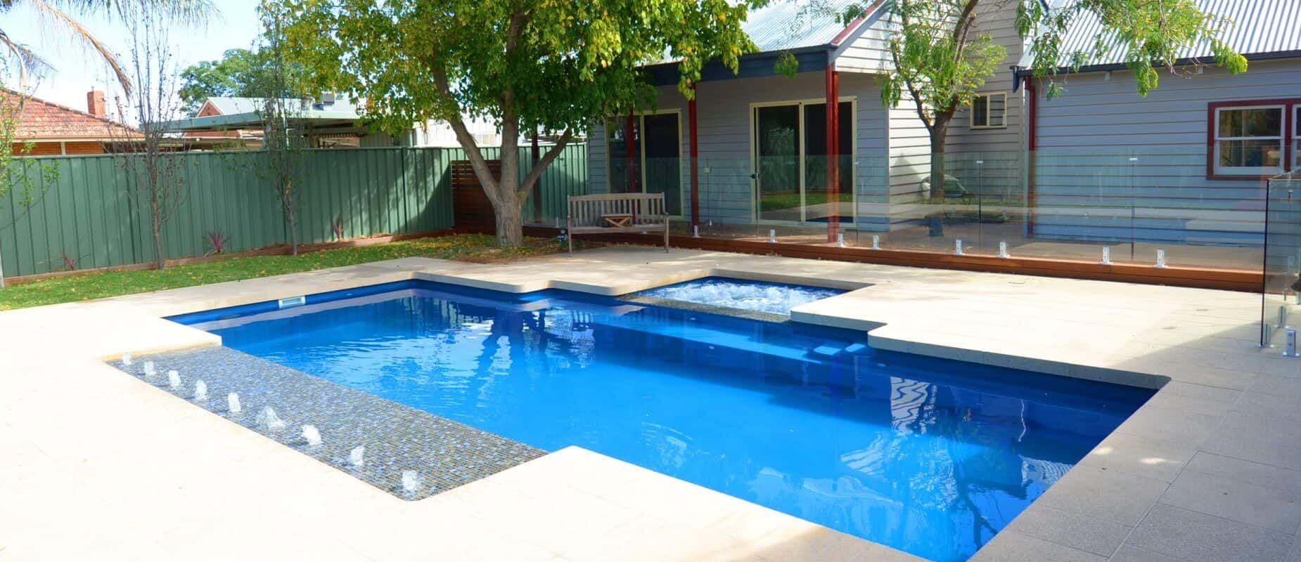A Large Swimming Pool is in the Backyard of a House — Azure Pools Mid North Coast In Taree, NSW
