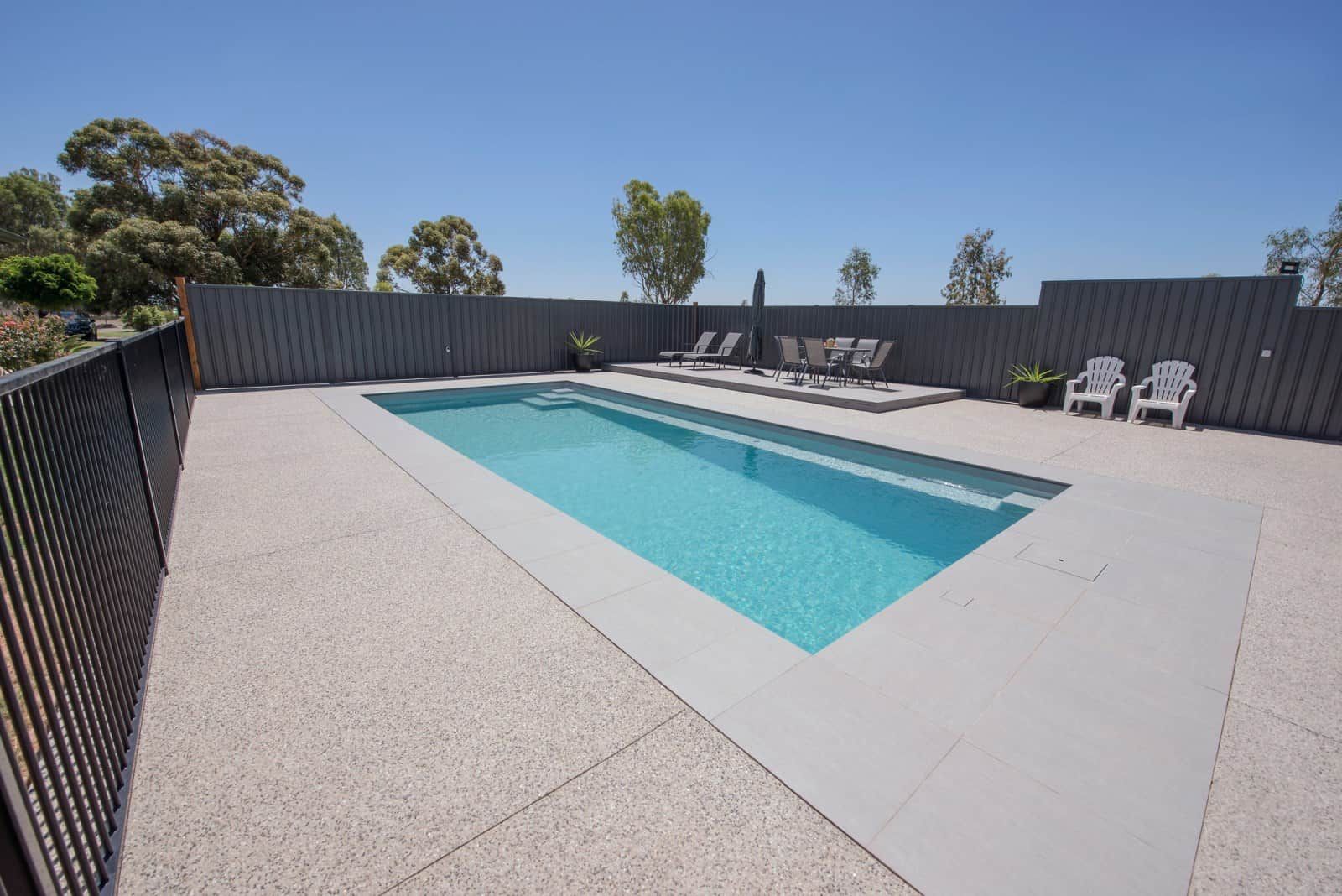 A Large Swimming Pool is Surrounded by a Fence and Chairs — Azure Pools Mid North Coast In Gloucester, NSW