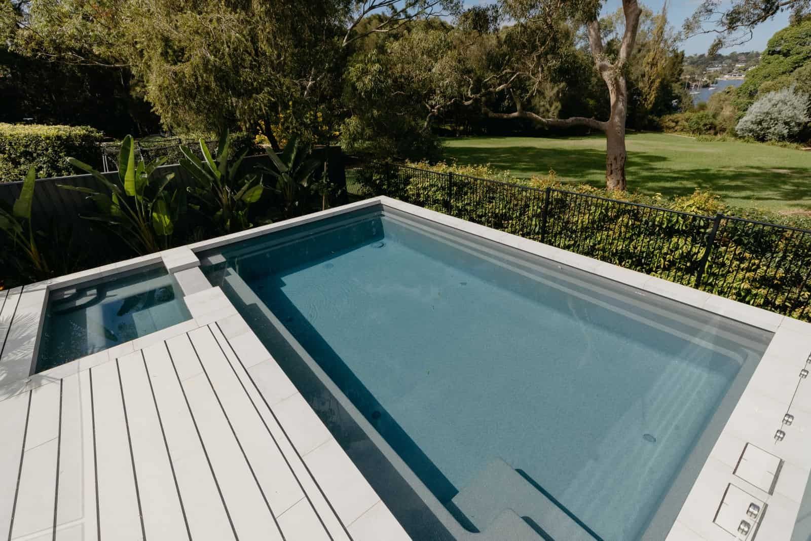 A Large Swimming Pool is Surrounded by Trees and a Deck — Azure Pools Mid North Coast In Gloucester, NSW
