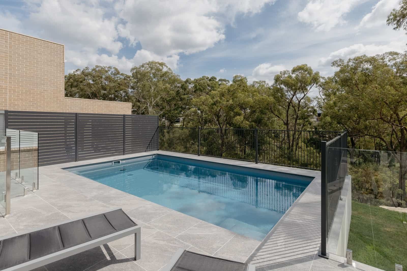A Large Swimming Pool is Surrounded by a Fence and Trees — Azure Pools Mid North Coast In Gloucester, NSW