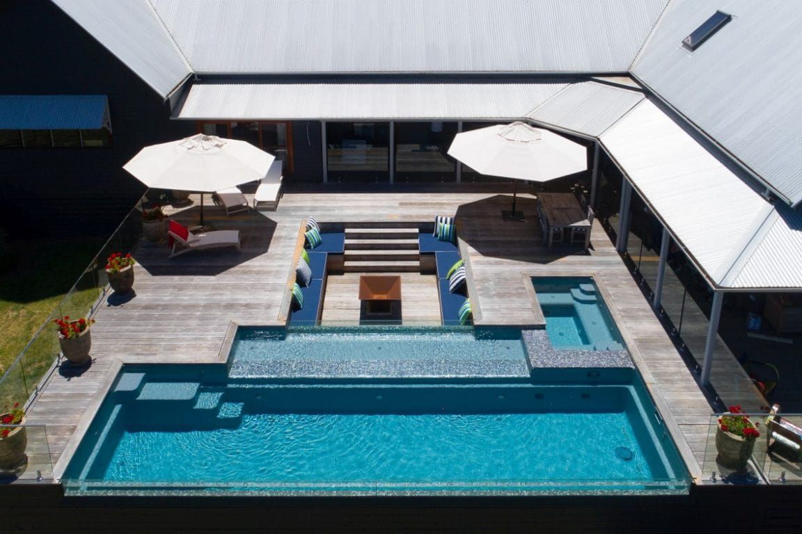 An Aerial View of a House With a Large Swimming Pool and Umbrellas — Azure Pools Mid North Coast In Nabiac, NSW