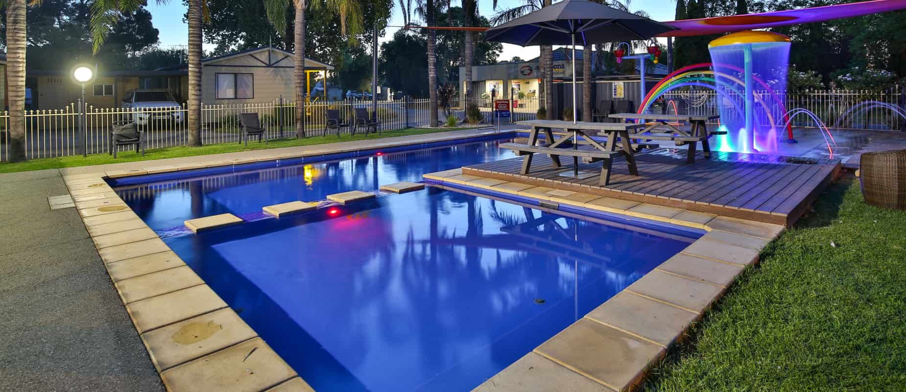 A Large Swimming Pool With a Water Slide in the Background — Azure Pools Mid North Coast In Taree, NSW