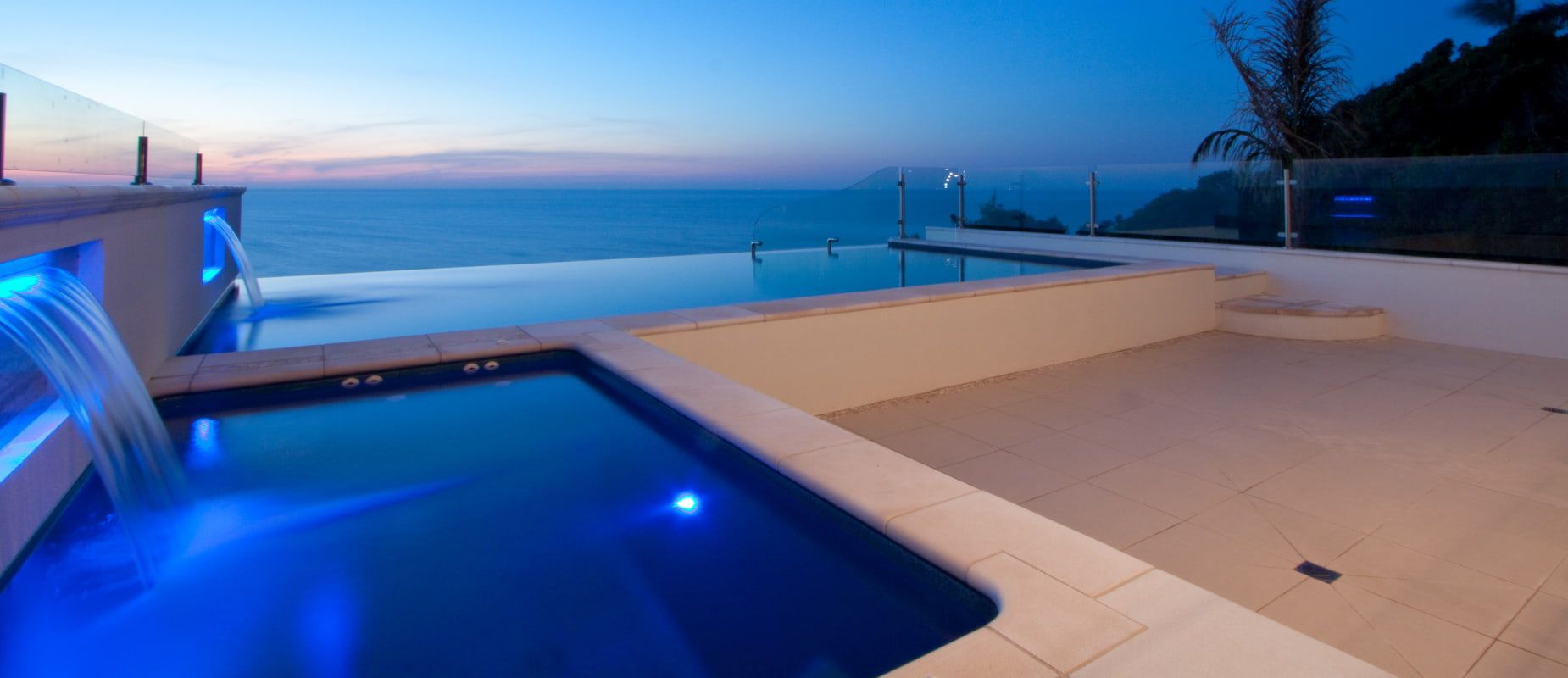 A Swimming Pool With a Waterfall and a View of the Ocean at Night — Azure Pools Mid North Coast In Harrington, NSW