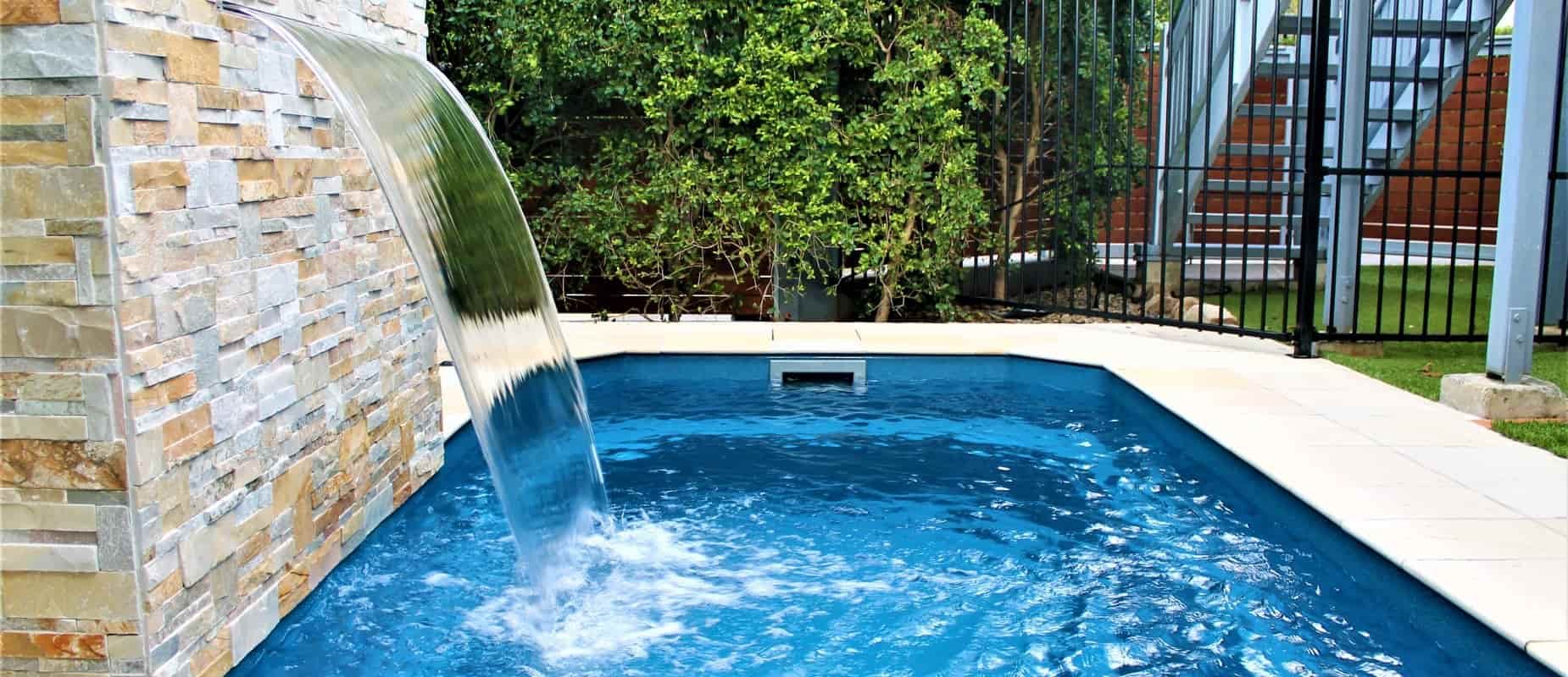 A Swimming Pool With a Waterfall on the Side of It — Azure Pools Mid North Coast In Forster, NSW