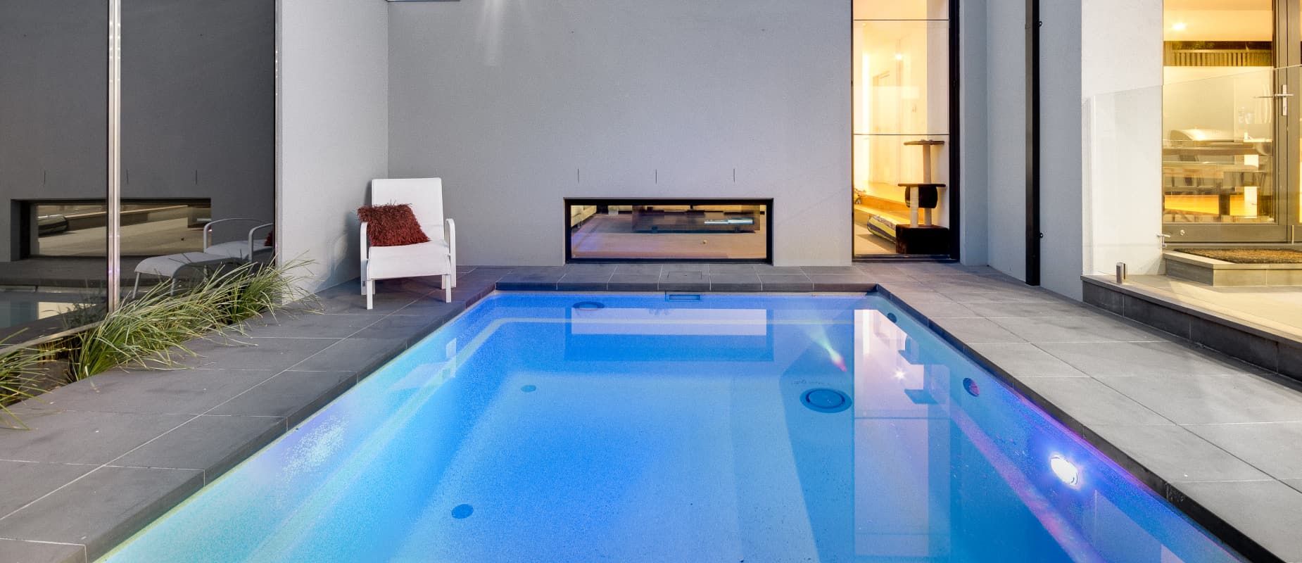 There is a Large Swimming Pool in the Backyard of a House With A White Chair Next To It — Azure Pools Mid North Coast In Diamond Beach, NSW