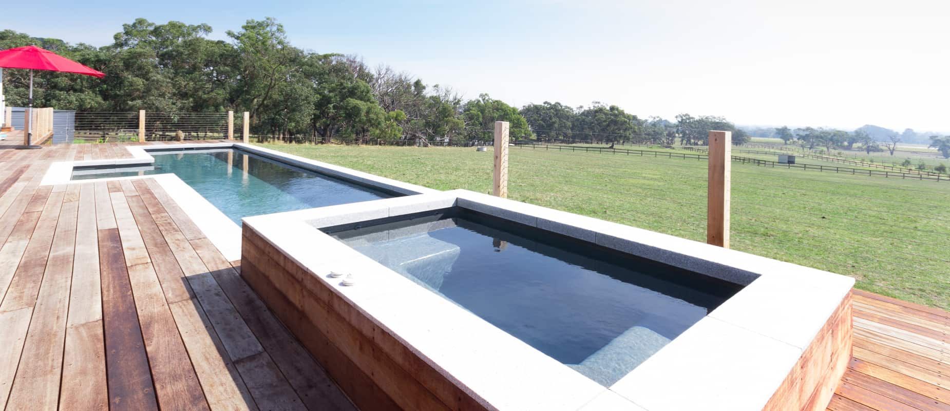 A Large Swimming Pool is Surrounded by a Wooden Deck — Azure Pools Mid North Coast In Harrington, NSW