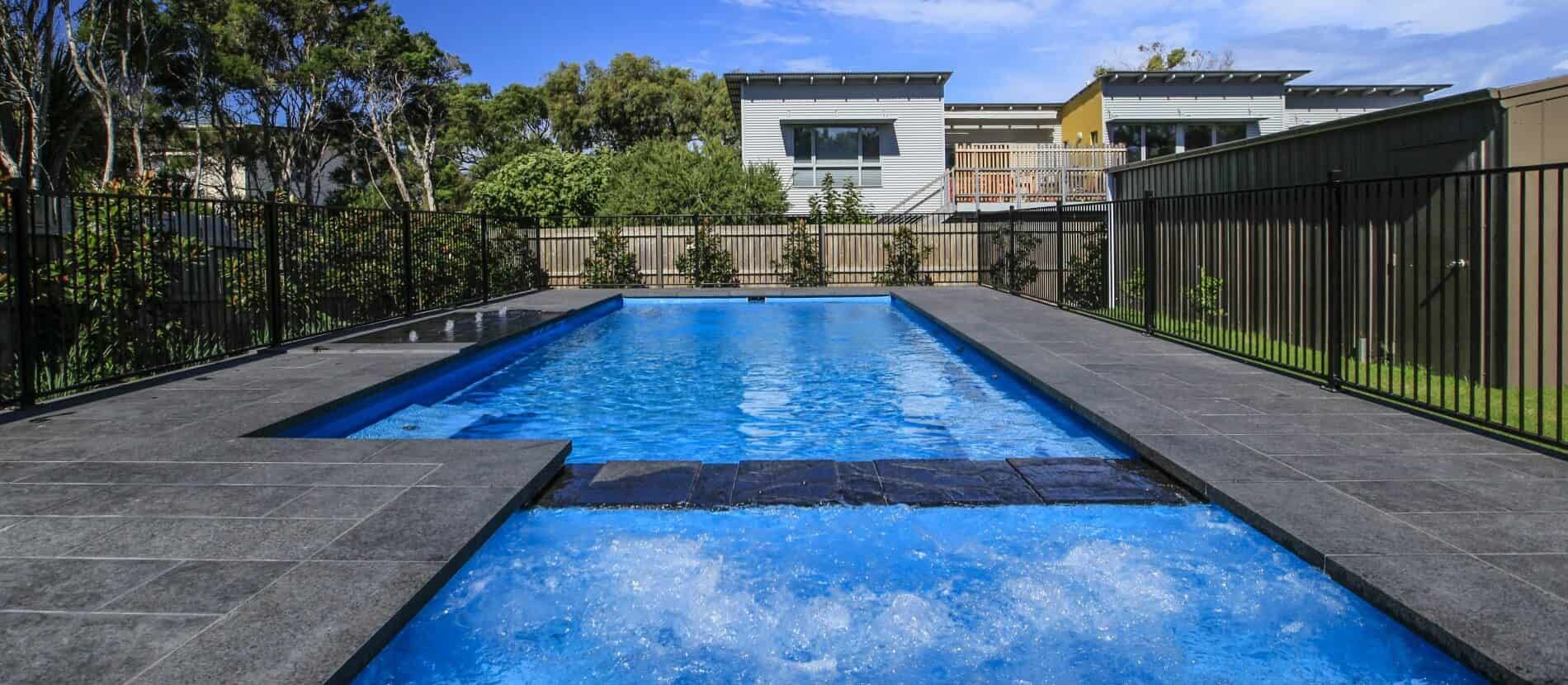 A Large Swimming Pool Surrounded by a Fence and a House — Azure Pools Mid North Coast In Harrington, NSW