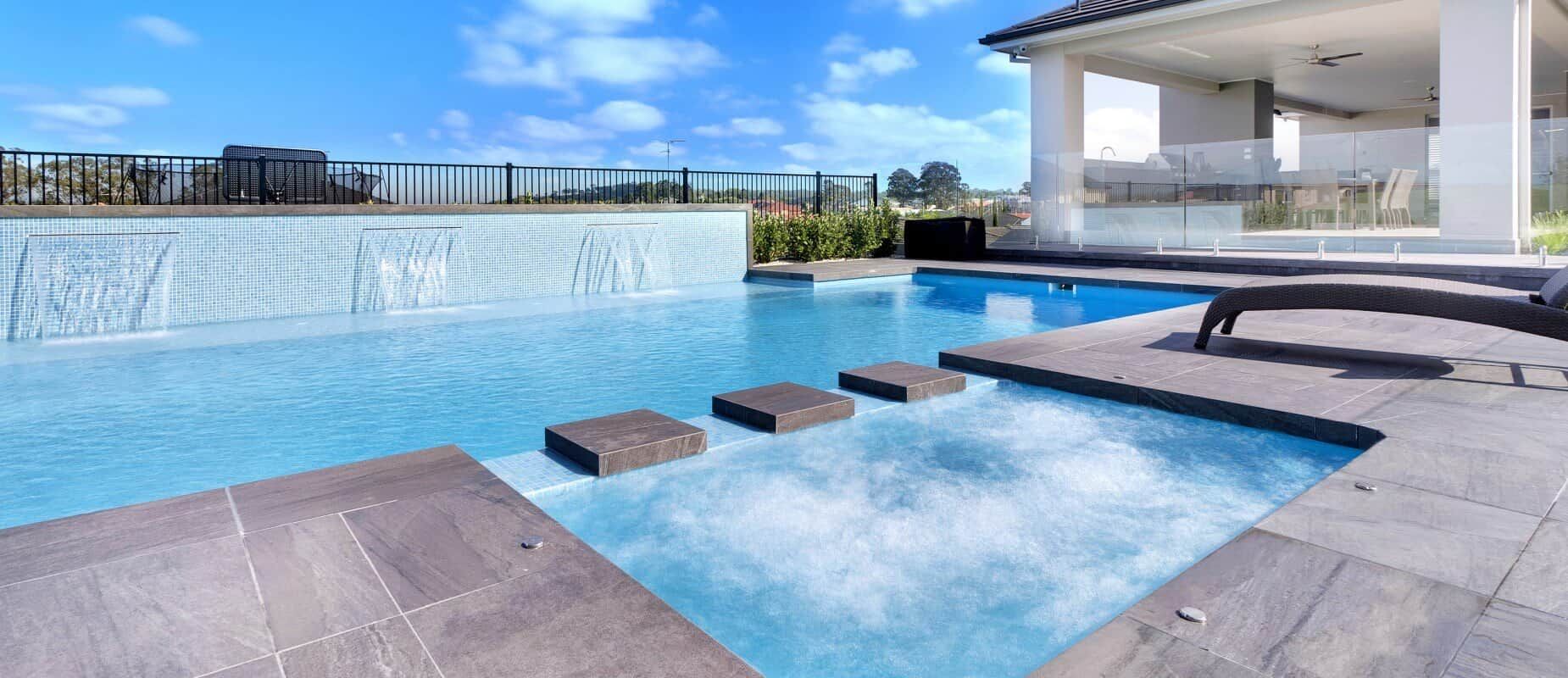 A Large Swimming Pool With a Waterfall and Steps Leading to It — Azure Pools Mid North Coast In Harrington, NSW