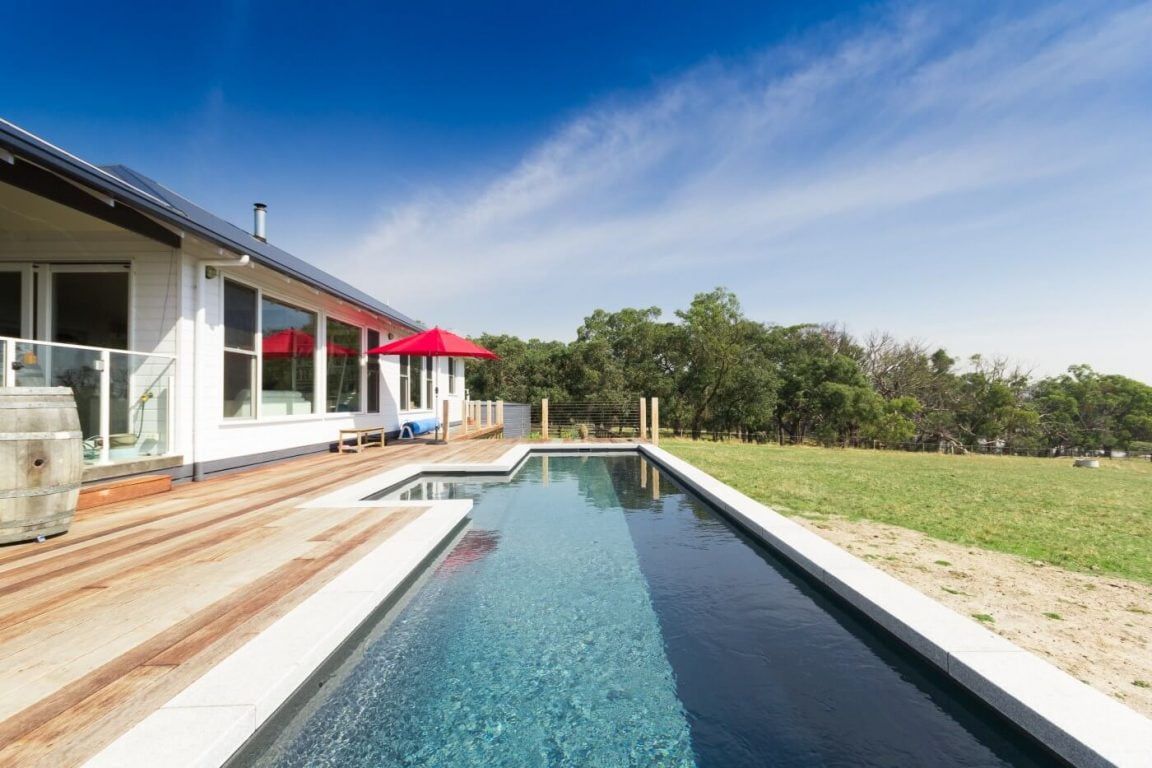 There is a Large Swimming Pool in Front of a House — Azure Pools Mid North Coast In Nabiac, NSW