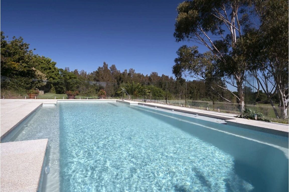 A Large Swimming Pool With Trees in the Background — Azure Pools Mid North Coast In Old Bar, NSW