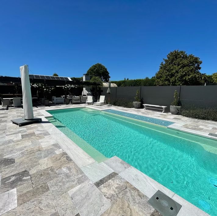 A Large Swimming Pool With a White Umbrella in the Foreground — Azure Pools Mid North Coast In Taree, NSW