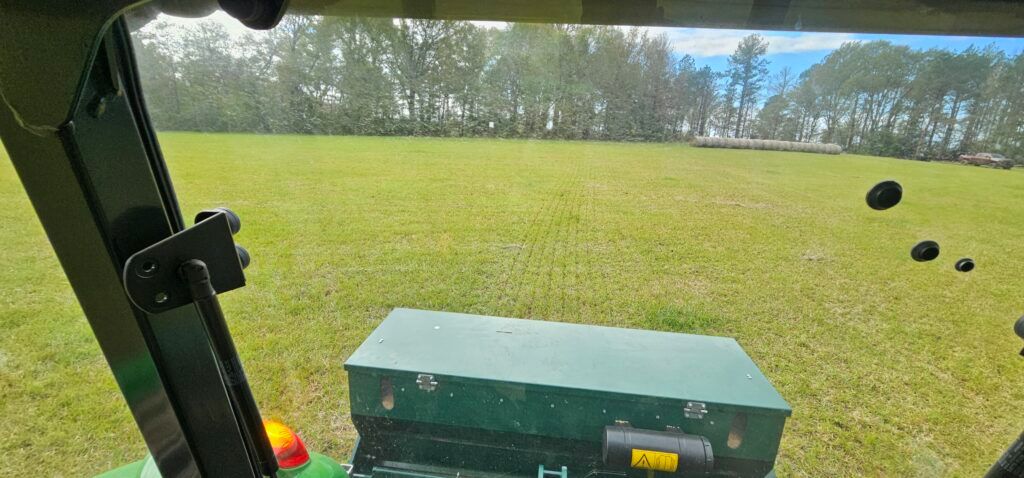 View from a tractor cab over a grassy field with a green equipment box in the foreground