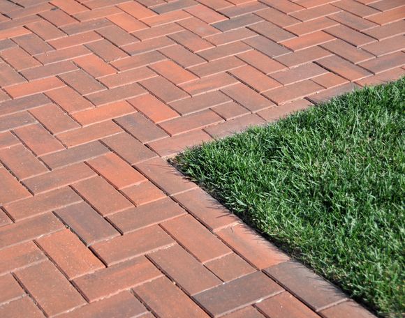 A person wearing gloves using a trowel to lay bricks, constructing a wall.