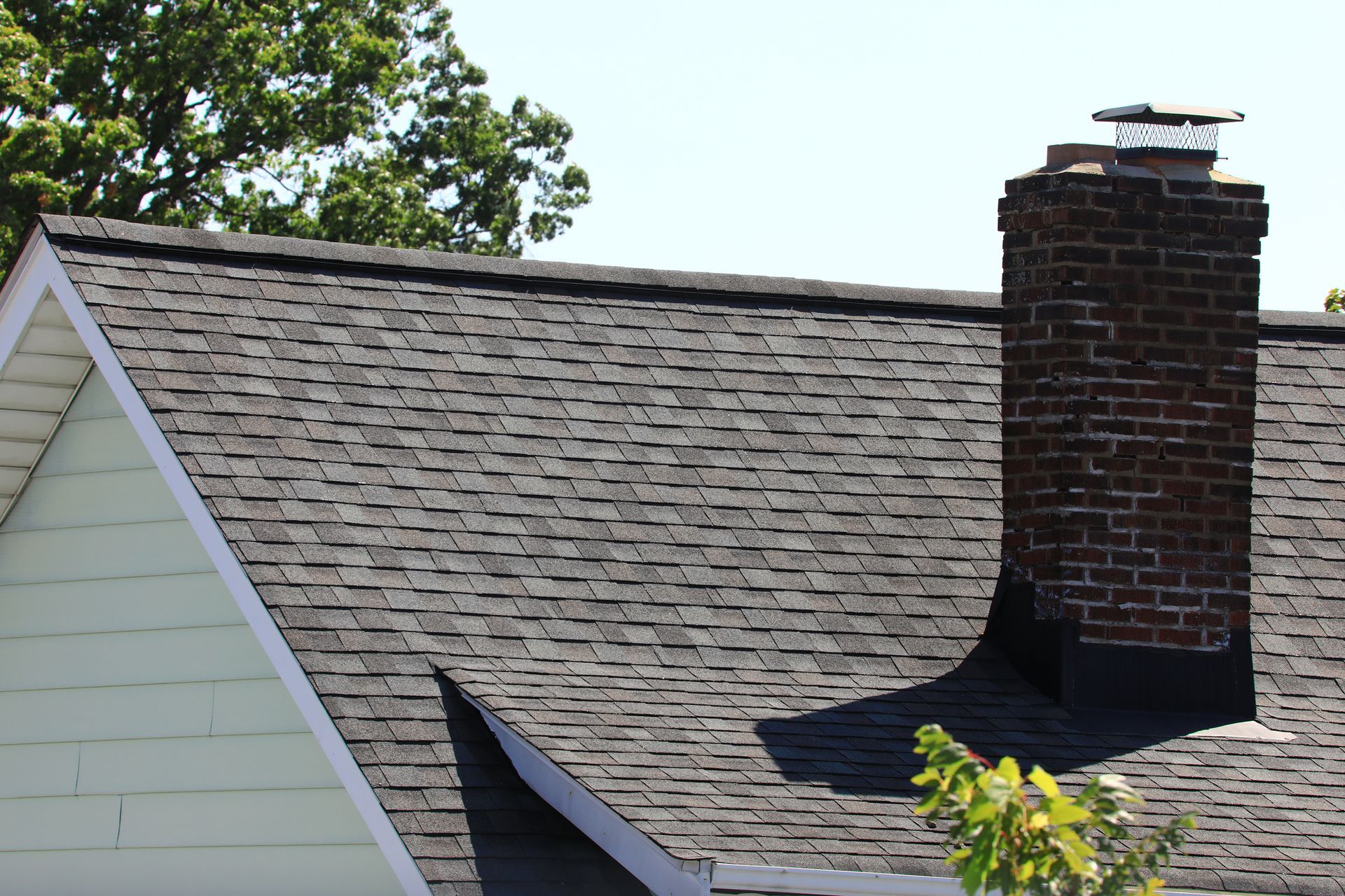 Roofer in hard hat replacing a brown tile on a tiled roof. Roofer in hard hat replacing a brown tile on a tiled roof.
