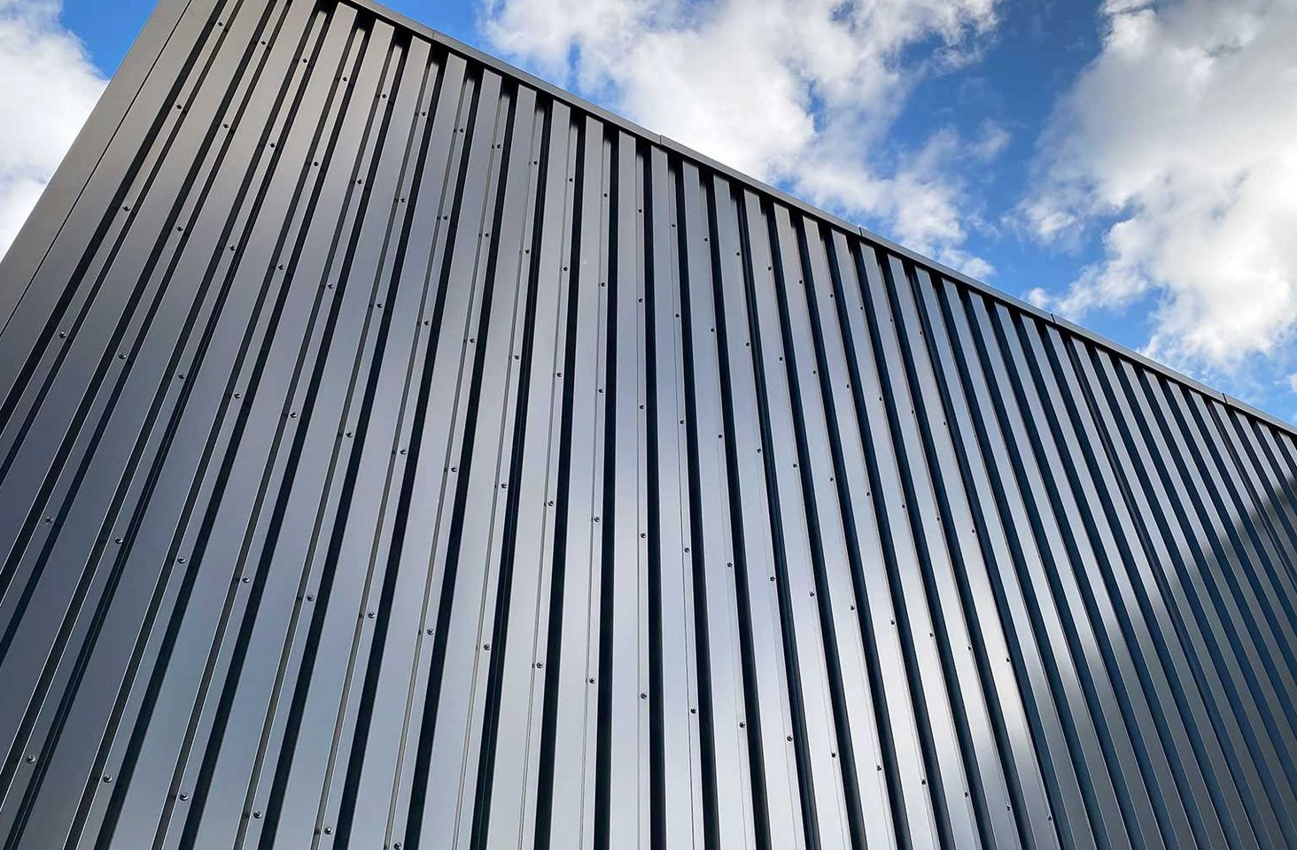Close-up of a modern building facade with gray panels and rows of blue-tinted windows.
