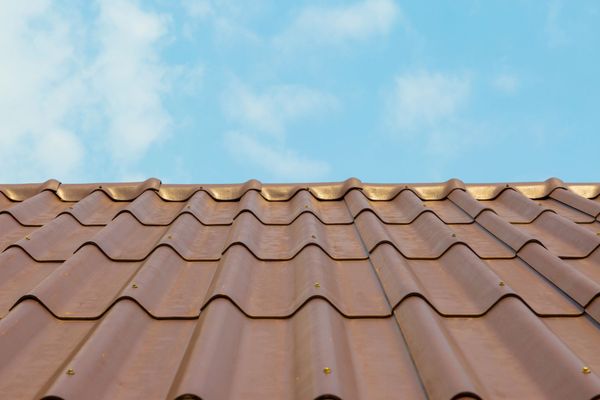 Brown tile roof against a light blue sky with wispy clouds.