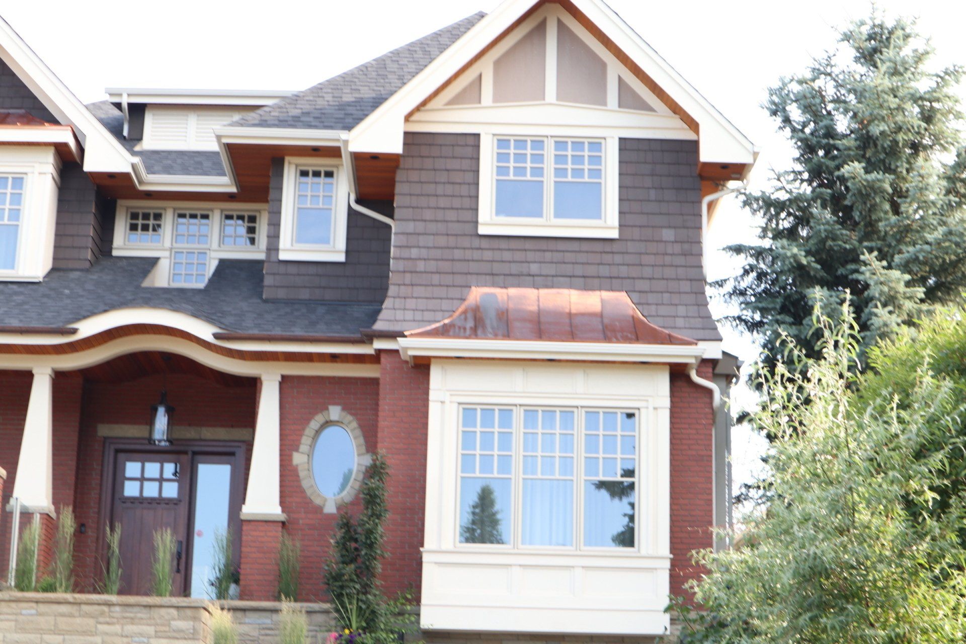 a brick house with a copper roof and a bay window