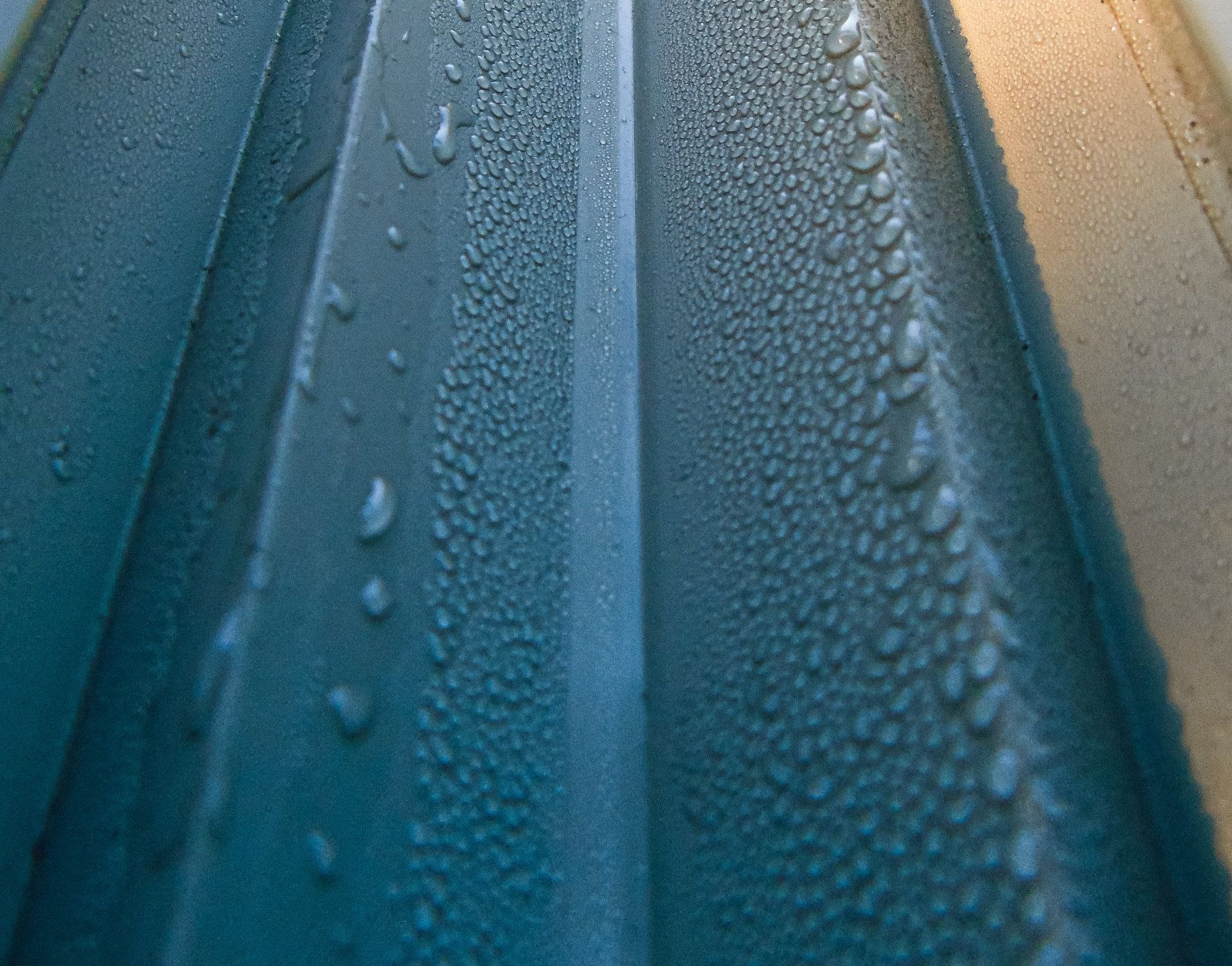 A close up of water drops on a blue surface.