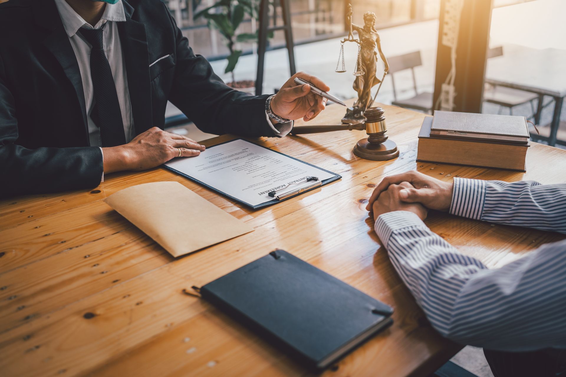 Lawyer pointing at document with client at wooden table.