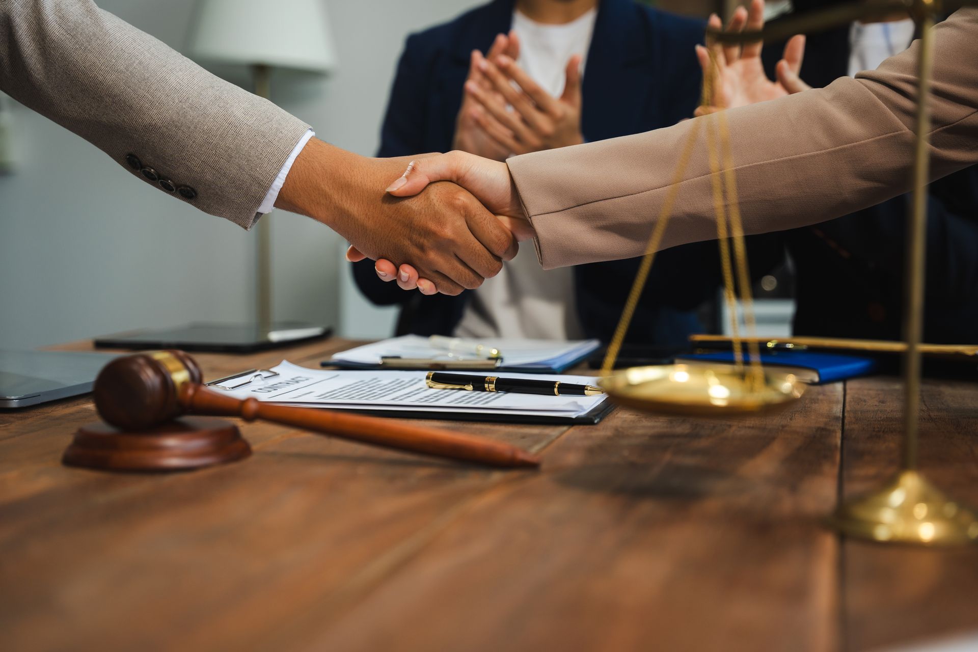 People shaking hands over a wooden table with gavel.