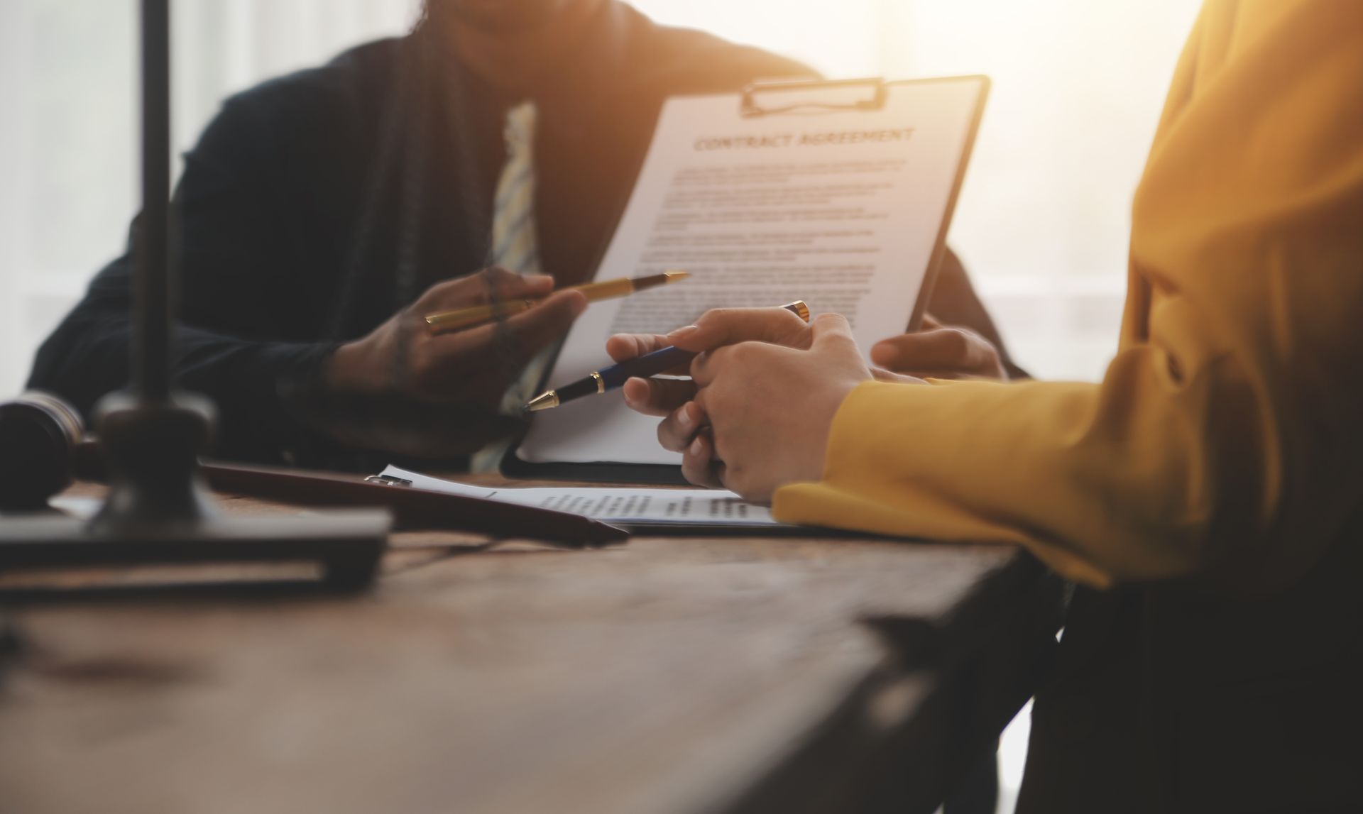 Two people reviewing and signing a contract at a desk.