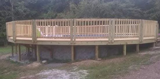 Wooden raised deck with railings in a wooded outdoor area