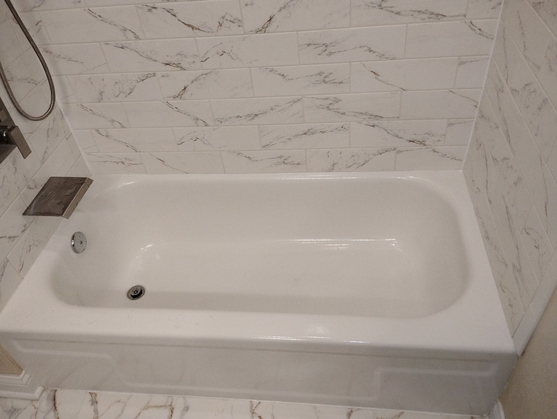 White bathtub with tiled walls in a bathroom corner.