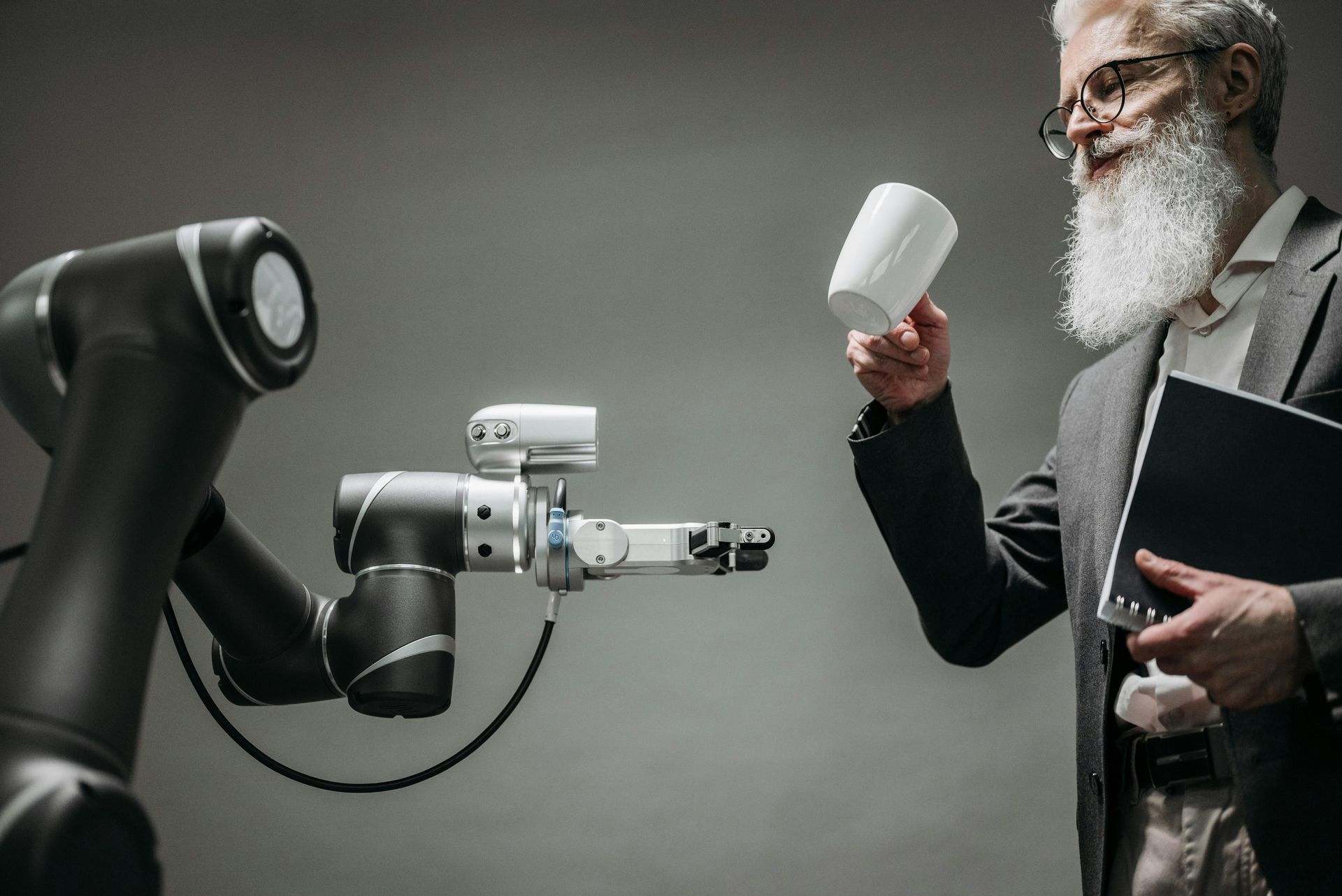 A man with a beard is standing next to a robot.