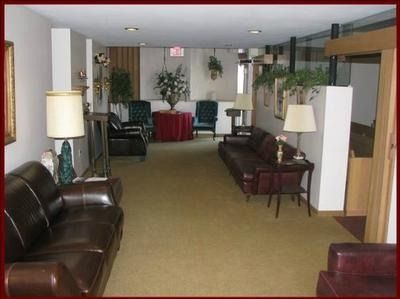 Long hallway lounge with couches, lamps, chairs, and a red table at the far end