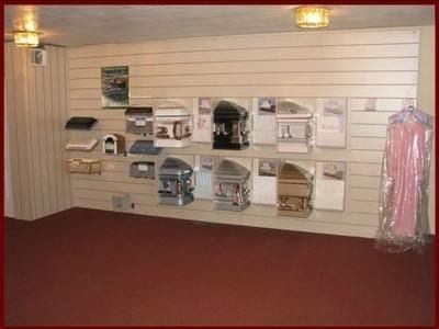 Small shop interior with wall-mounted pet carriers and accessories on display, red carpeted floor.