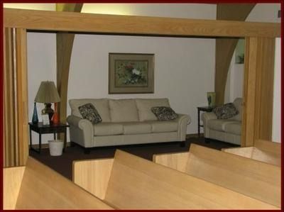 Living room with beige sofa, armchair, lamp, and framed wall art viewed through a wooden frame