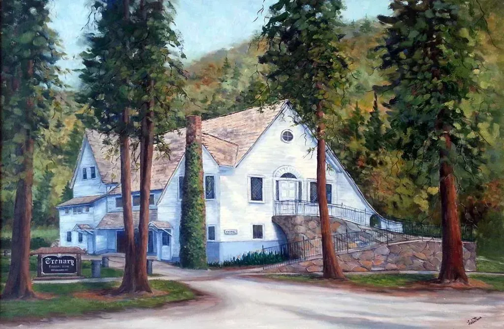 White house with orange roof behind trees, beside a curving road and stone wall.