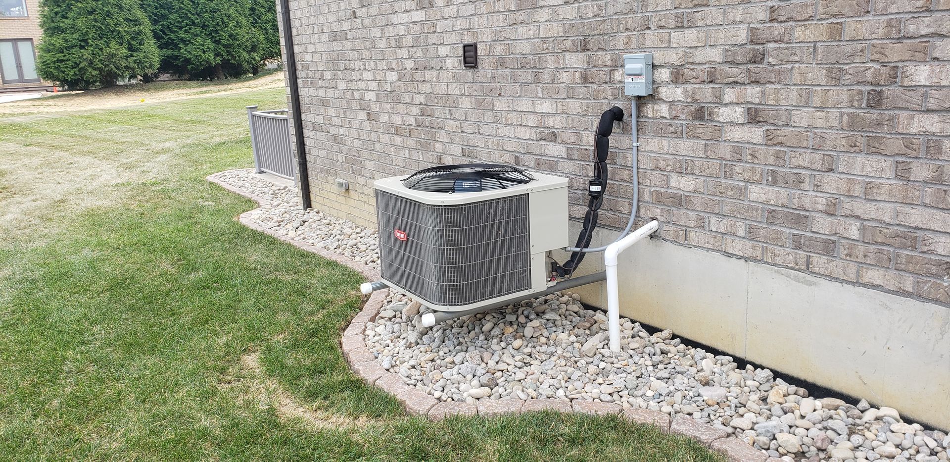 An air conditioner is sitting on the side of a brick building.