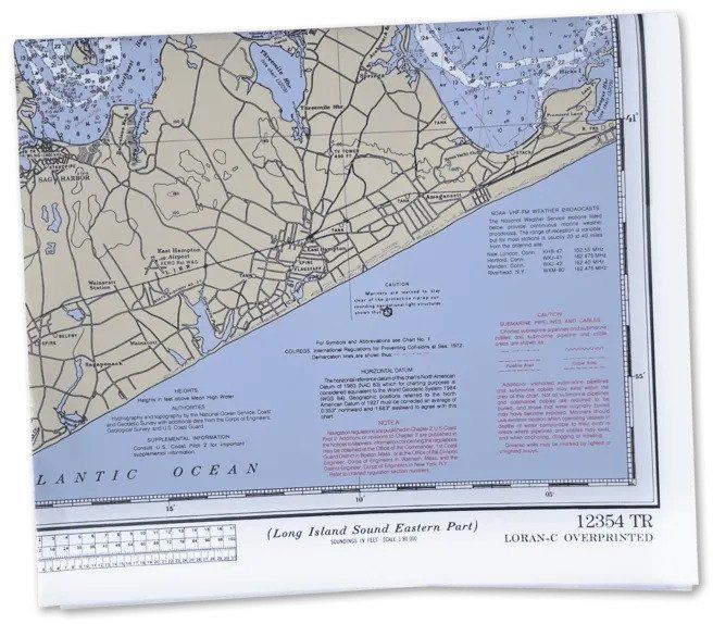 Folded nautical chart with blue coastline, tan land, and grid lines on a white surface